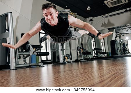 Fit Young Man Doing Kip-up Movement In Gym