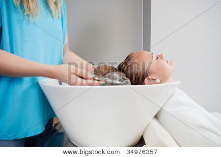 Uvolněné mladá žena jí umýt před účes v beauty salonu