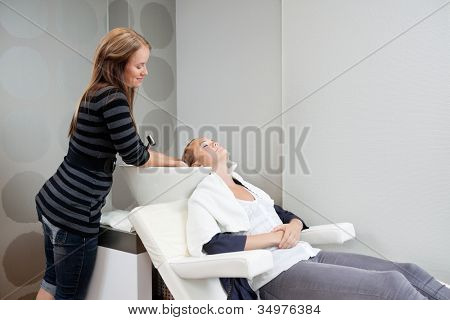 Samice kosmetička mytí vlasů ze svého zákazníka před účes v beauty salonu