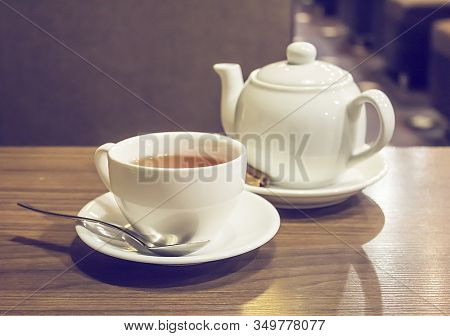 Porcelain Teapot, Teacup, Spoon And 
Canella On Wooden Table.