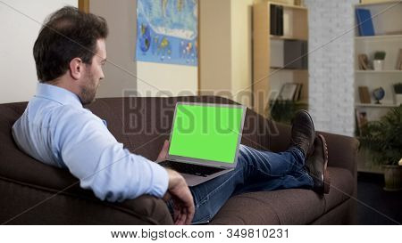 Relaxed Male On Couch Using Green Screen Laptop Shopping Online, Booking Service