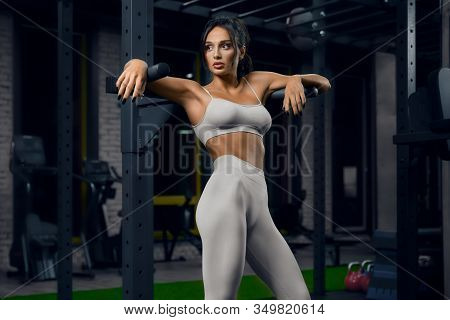 Front View Of Female Bodybuilder In Beige Sportswear Posing Near Parallel Bars. Srtong Woman With Fi