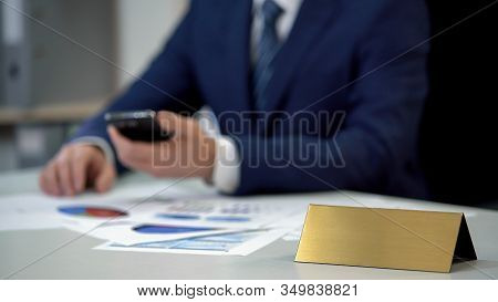 Business Man In Suit Using Phone, Annual Report On Table, Golden Blank Nameplate
