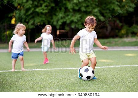 Football Game: Team Of Toddlers Playing Soccer On Green Field: Three Children, Two Boys (one Is Bare