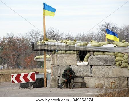 Volnovakha, Ukraine - October, 2014: Ukrainian Border Guard Sitting Near The Concrete Pavement At Th
