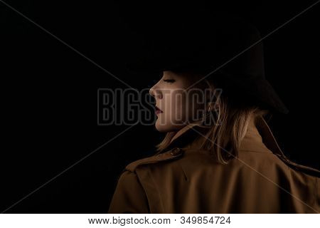 Retro Gangster Woman In A Brown Cloak And Black Hat. Photoshoot In The Style Of The Mafia. Dark Blur