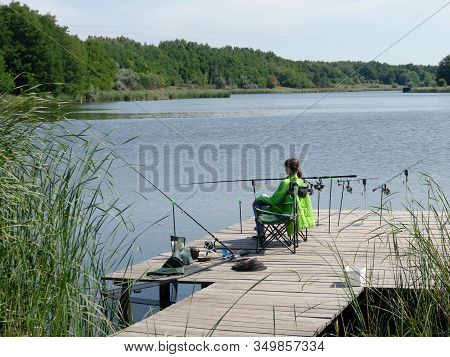 Girl Carp Fishing On Beautiful Blue Lake With Carp Rods And Rod Pods In The Summer Morning. Fishing 