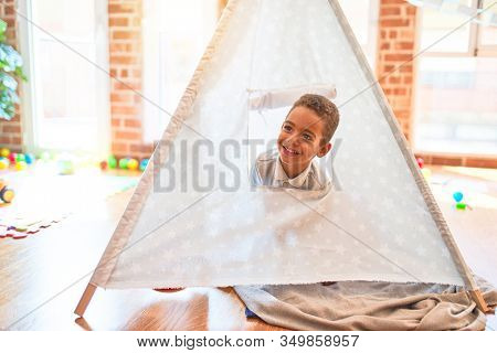 Beautiful african american toddler playing inside tipi smiling at kindergarten