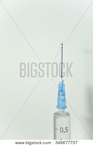 Clear Drop Of The Vaccine On The Top Of The Needle Of Syringe On The White Background