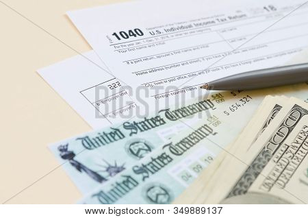 1040 Individual Income Tax Return Form With Refund Check And Hundred Dollar Bills On Beige Backgroun