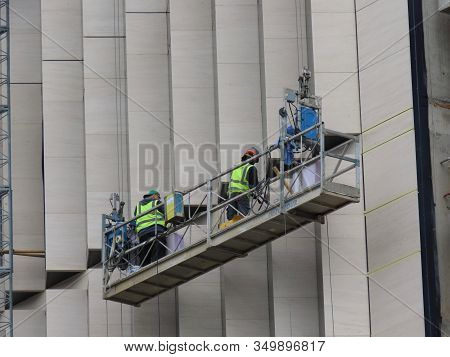 Luxembourg City, Luxembourg - May 23, 2019. Construction Workers In Hanging Lift Doing Finishing Tou