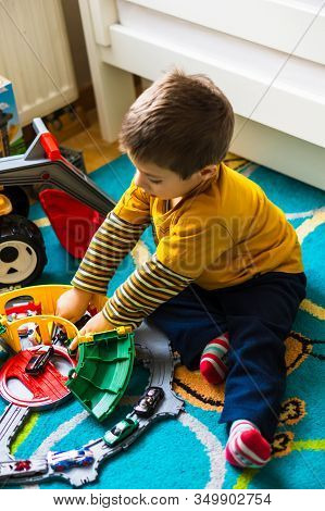 Poznan, Poland - January 19, 2020: Young Polish Boy Sitting On A Floor Playing With A Plastic Toy Tr