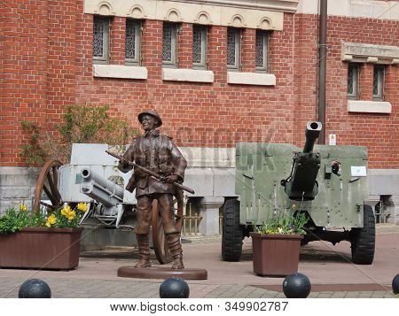 Albert, Somme, France - May 1, 2019. Bronze Figure Of A Soldier And Historic Artillery Guns Next To 