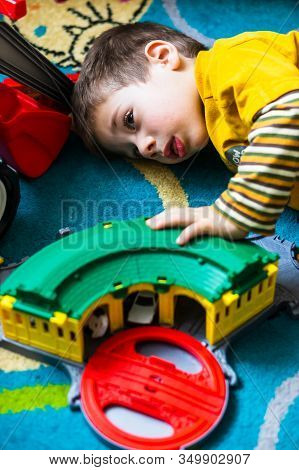 Poznan, Poland - January 19, 2020: Small Young Kid Playing With A Plastic Toy Train Station While La