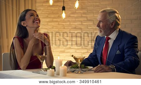 Beautiful Lady Laughing And Flirting With Old Rich Man In Restaurant, Escort