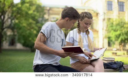 Teenagers Students Reading Books In Park, Sitting On Bench, Preparing For Test