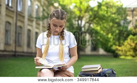 Young Woman Reading Book On Bench On Campus, Preparing Homework, Education