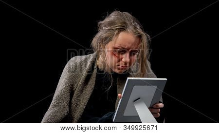 Desperate Marital Mistreatment Victim With Wound On Face Looking At Photo, Pain