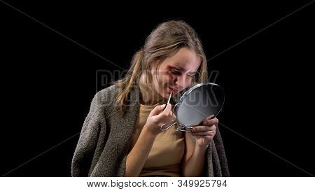 Female With Wounded Cheek Applying Lipstick Looking In Mirror, Crying In Despair