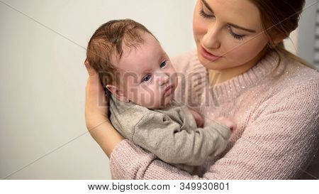 Attentive Female Babysitter Holding Little Adorable Baby And Talking To Him