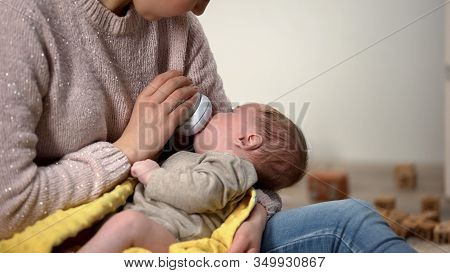 Babysitter Feeding Adorable Little Girl From Bottle, Anticolic Milk Formula