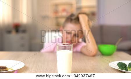 Capricious Male Kid Looking Sadly Glass Of Milk On Kitchen Table, Healthy Meal