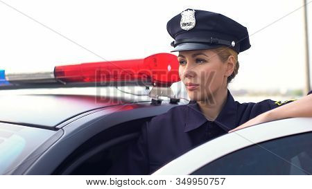 Strong Lady In Police Uniform Standing Near Patrol Car, Protecting Law And Order