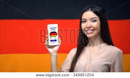 Nice Woman Holding Phone With Language Study App, German Flag On Background