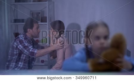 Sad Girl With Teddy Bear On Rainy Day, Father Slapping Mother On Background