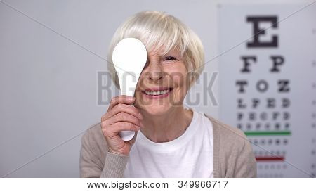 Retired Female Closing Eye And Smiling To Camera, Successful Cataract Surgery