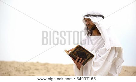 Arab Reading Koran In Desert, Meditating And Reflecting On Muhammad Teachings