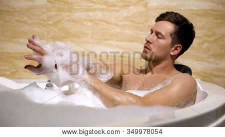 Scrupulous Man Soaping Himself With Loofah, Taking Bath With Foam, Cleanness