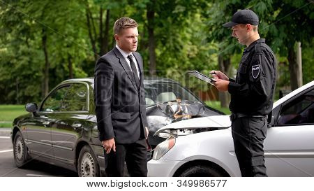 Male Police Officer Filling Car Crash Report, Businessman Standing Broken Auto