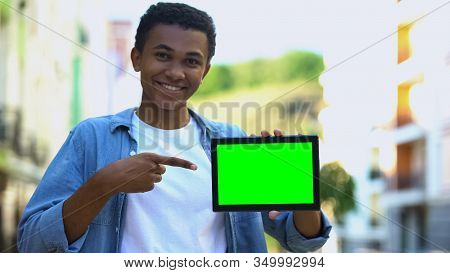 Excited Black Boy Pointing Finger At Green Screen Tablet In Hand, Advertising