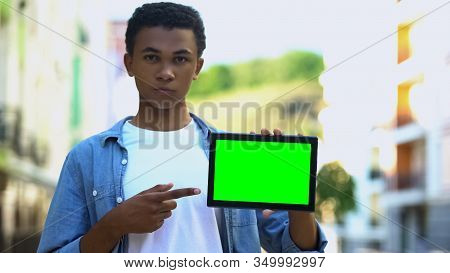 Serious Mixed-race Teenager Pointing Finger At Green Screen Tablet, Work App