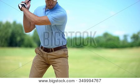 Serious Golfer Hitting Ball In Backswing Position, Preparing For Competition