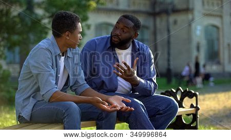 Father Arguing Teenage Son Sitting On Campus Bench, Puberty Age Difficulties