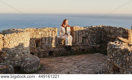Beautiful Girl With White Dress Explores An Ancient Italian Castle At Sunset. Close-up