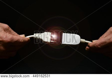 A Man Holds Two Disconnected Electric Cables In His Hand On Black Background. Electricity Supply Pro