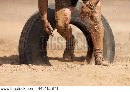 Mud Race Runners.the Participante Overcoming The Obstacle Made Of Tire