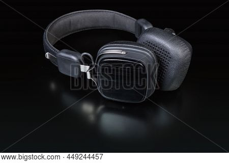 Black Wireless High-fidelity Headphones On A Dark Matt Reflective Surface In Selective Focus