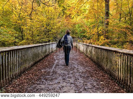 Attractive 30 Year Old White Woman Walking Away On A Wooden Pedestrian Bridge In Apark With Colorful
