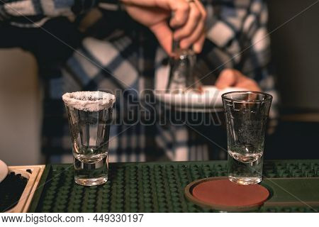Two Empty Shot Glasses With Salt At Rim On Bar Counter For Serving Tequila