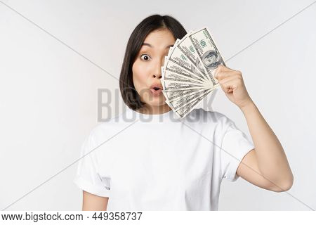Happy Asian Girl Holding Money, Cash Near Face, Concept Of Microcredit And Finance, White Studio Bac