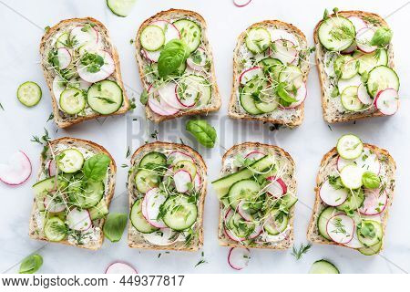 Top Down View Of Cucumber And Radish Tartines Garnished With Herbs.