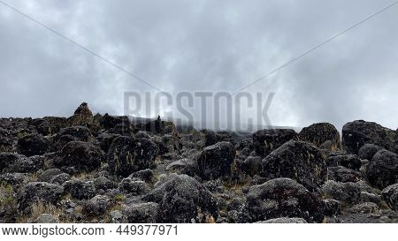 Large Stones Of Solidified Lava Are Scattered Across The Mountainous Area. Foggy Mountain Landscape.