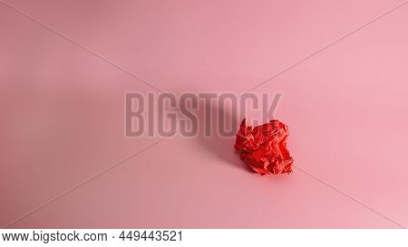 Crumpled Red Paper On A Pink Background With A Trend Shadow. Screwed Up Craft Paper Ball. Junk Paper