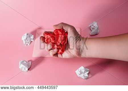 Hand Of Aggressive And Frustrated Man Squeezing Heart Out Of Crumpled Paper. Envelope With Lumps Of