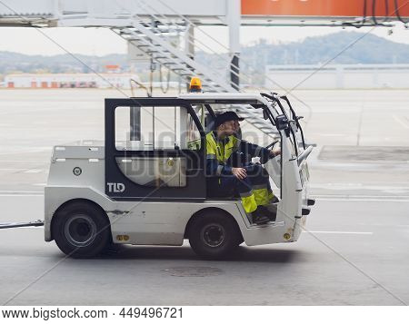 Russia, Sochi 02.11.2021. An Airport Mulag Car With Two Airport Employees In Overalls Is Driving Alo