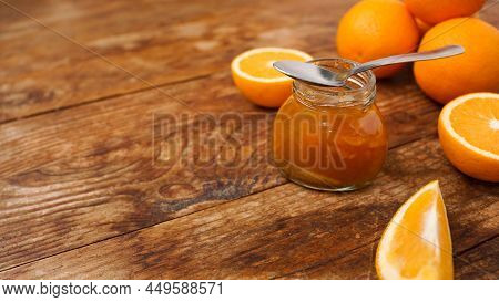 Jar Of Orange Jam And A Metal Spoon On Wooden Background From Top View. Place For Text. Homemade Ora